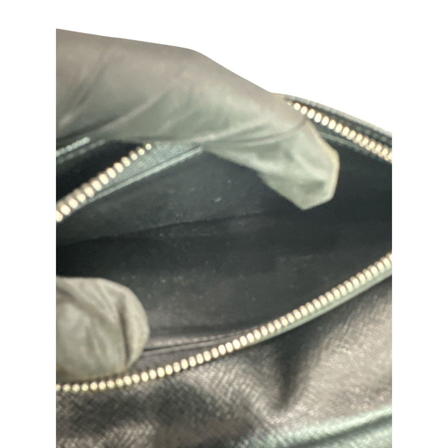 Close-up of a black leather jacket with a zipper, worn by a person.