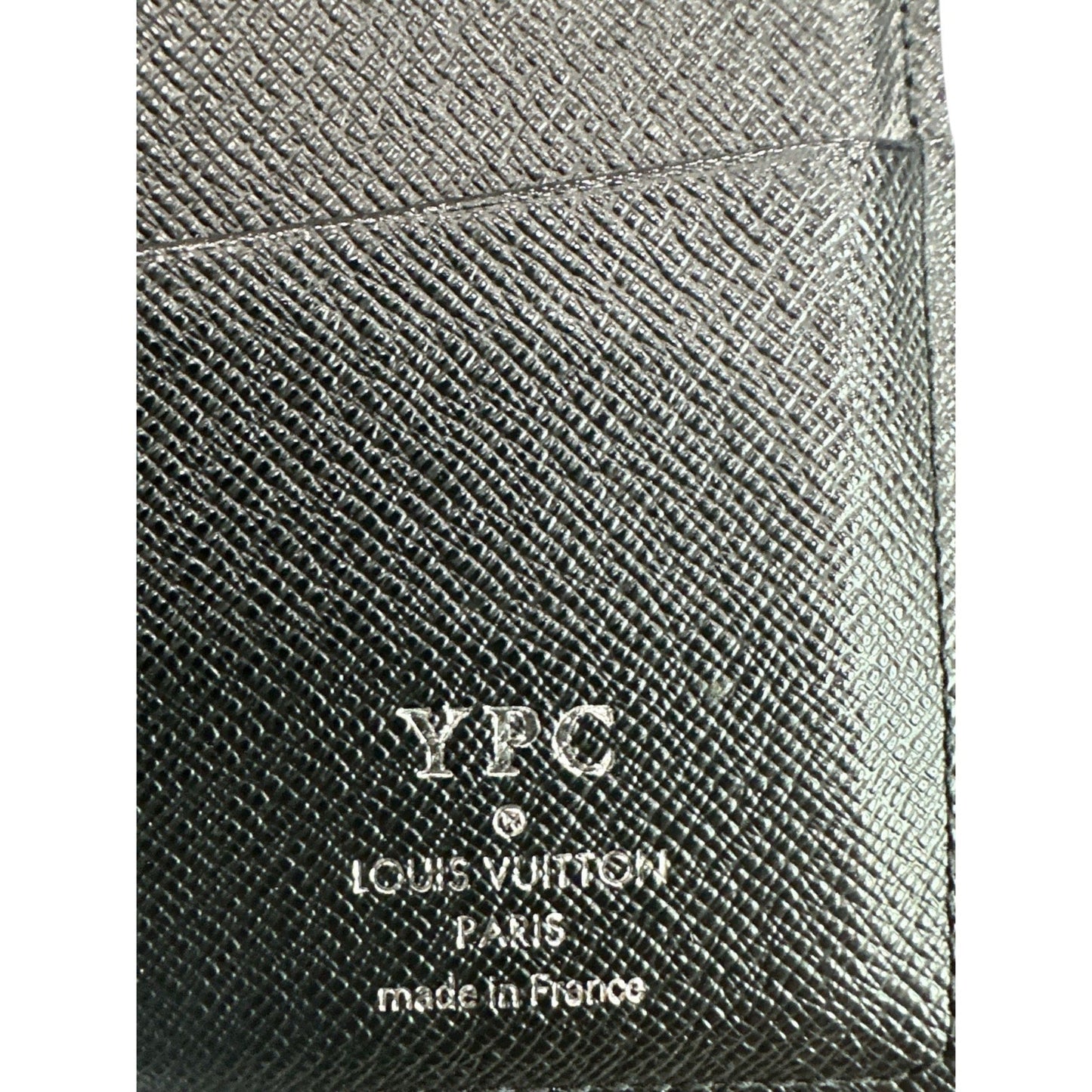 Close-up of a textured black leather product with 'YPC' and 'Louis Vuitton' branding.