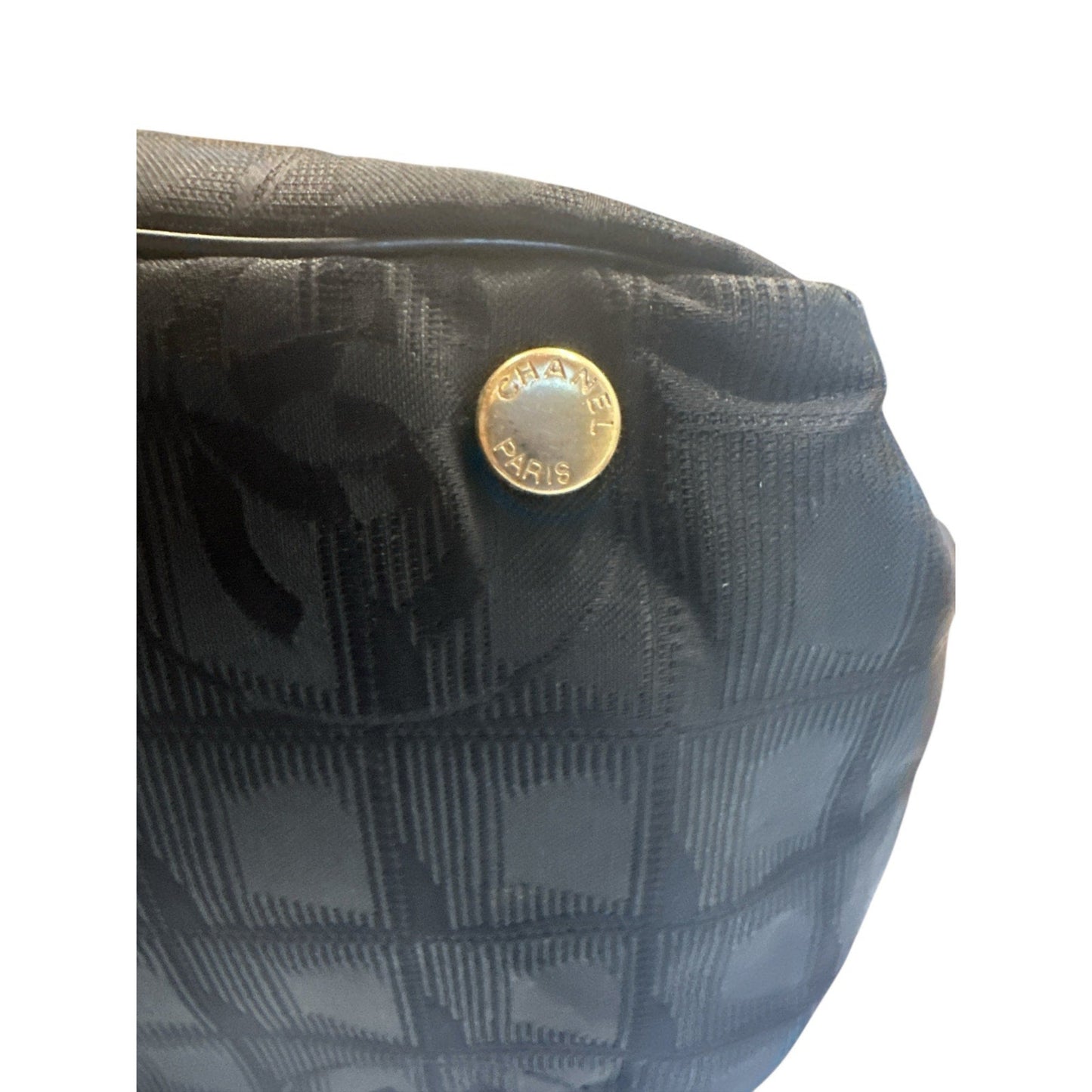 Close-up of a Chanel bag with a gold logo on a white background