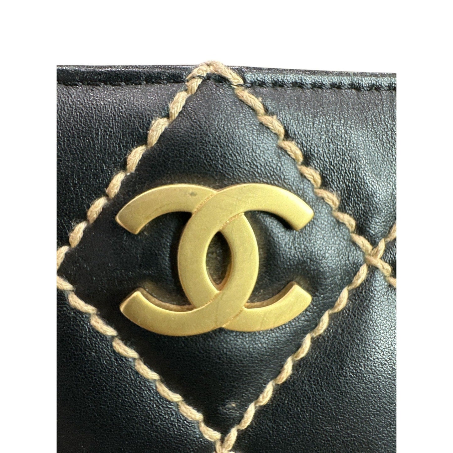 Close-up of a black leather product with gold stitching and Chanel logo.