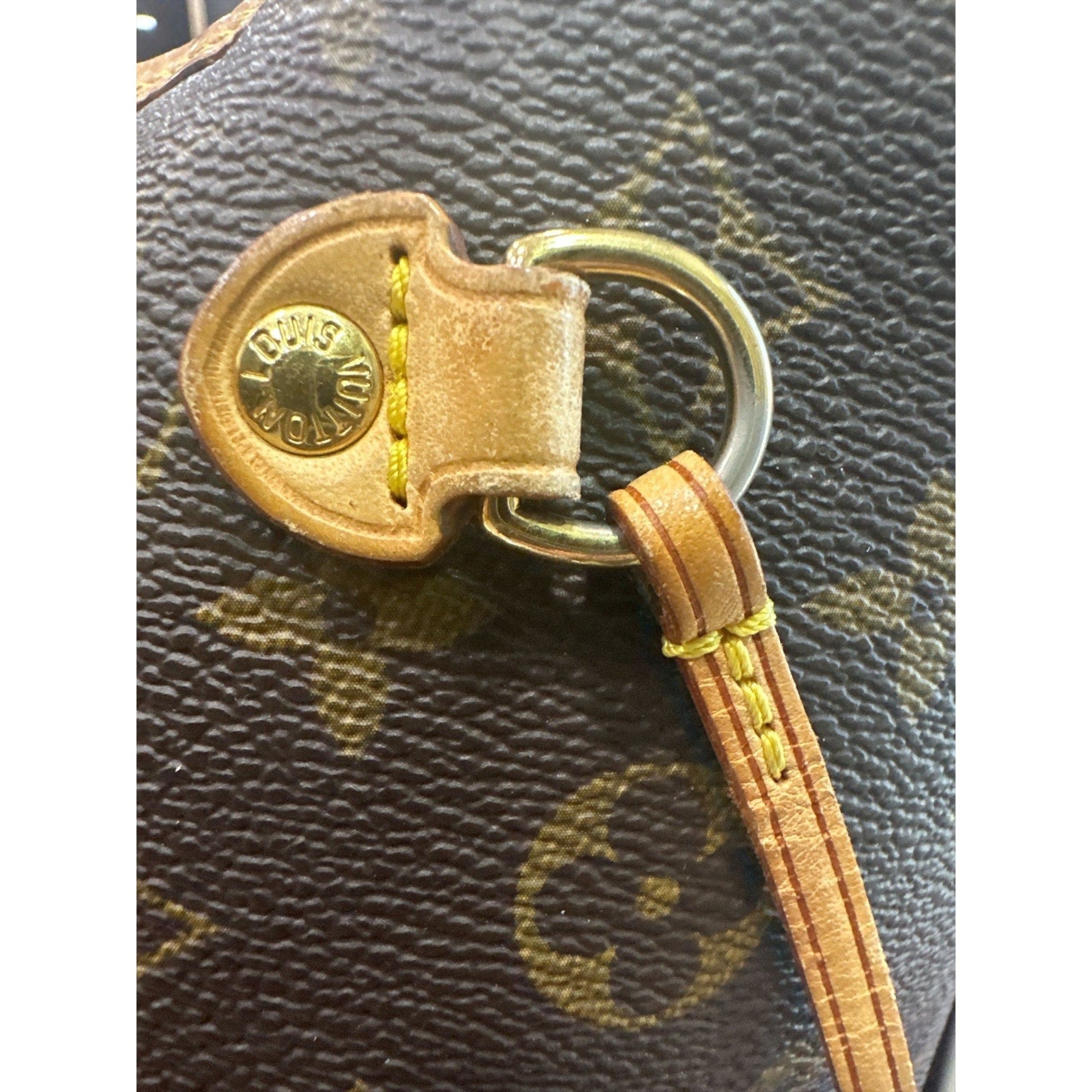 Close-up of a gold keychain with a logo on a textured brown surface