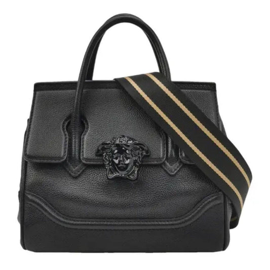 Black leather handbag with a gold stripe and emblem on a white background