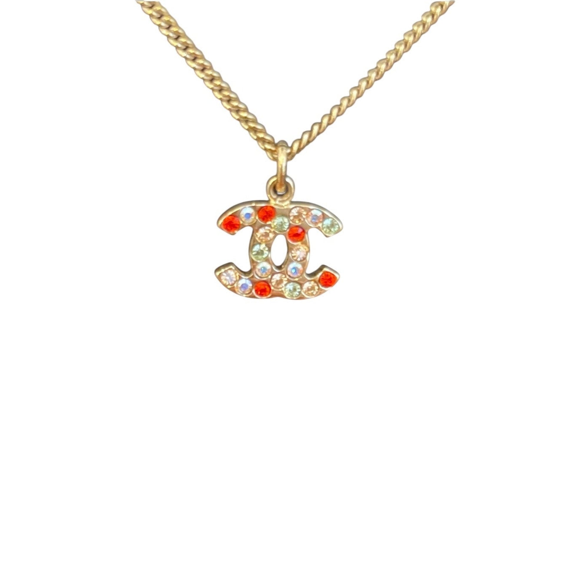Gold necklace with a colorful 'CC' pendant on a white background