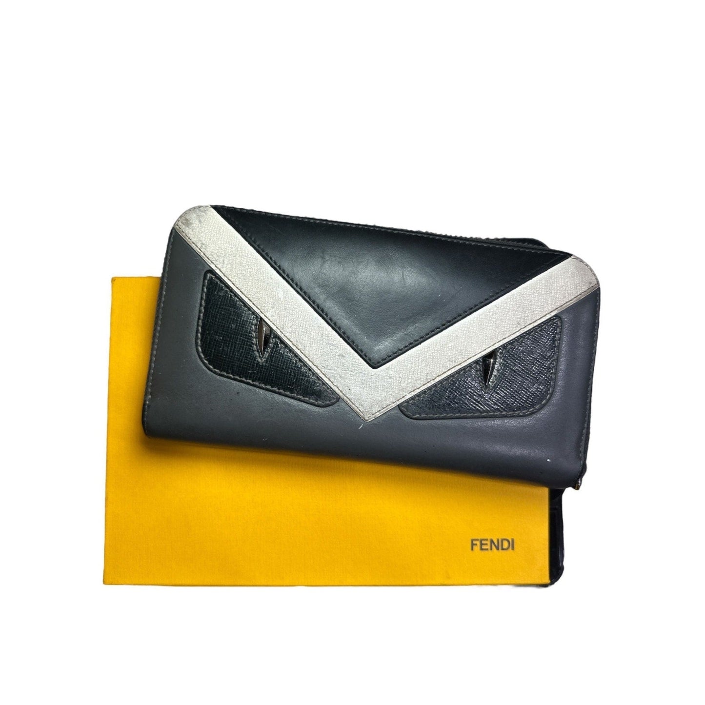 Black and white clutch bag with a yellow Fendi dust bag on a white background