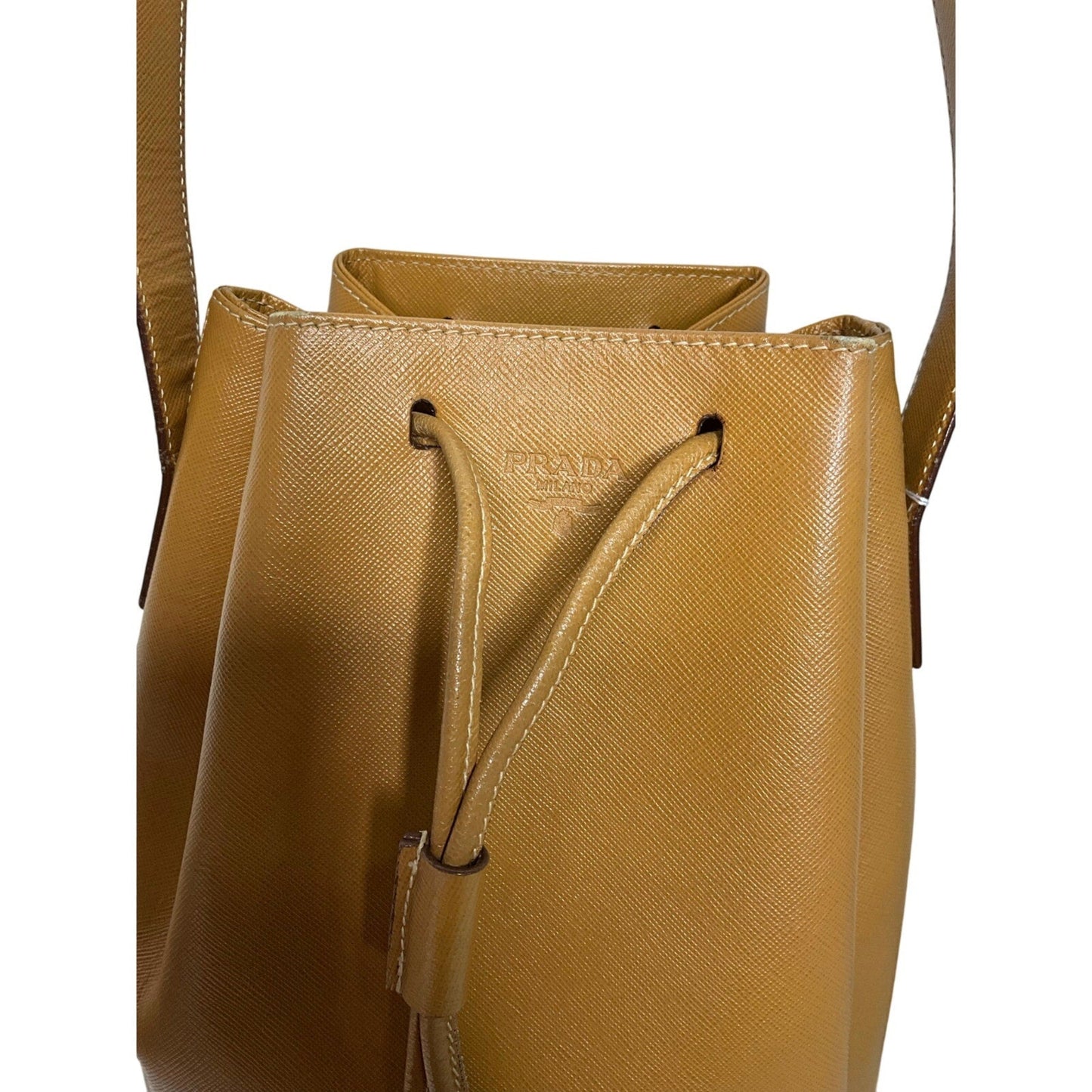 Tan leather bucket bag with Prada logo on a white background