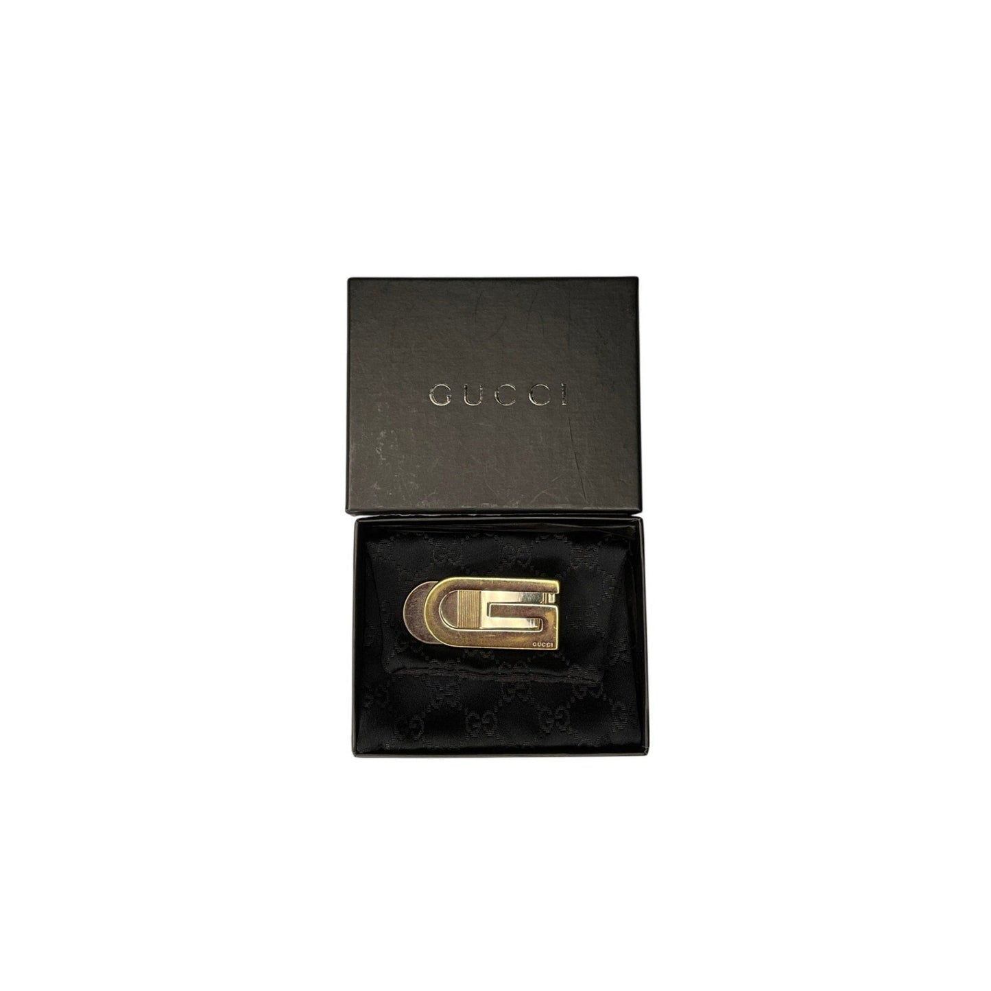 Gold Gucci belt buckle in a black box on a white background