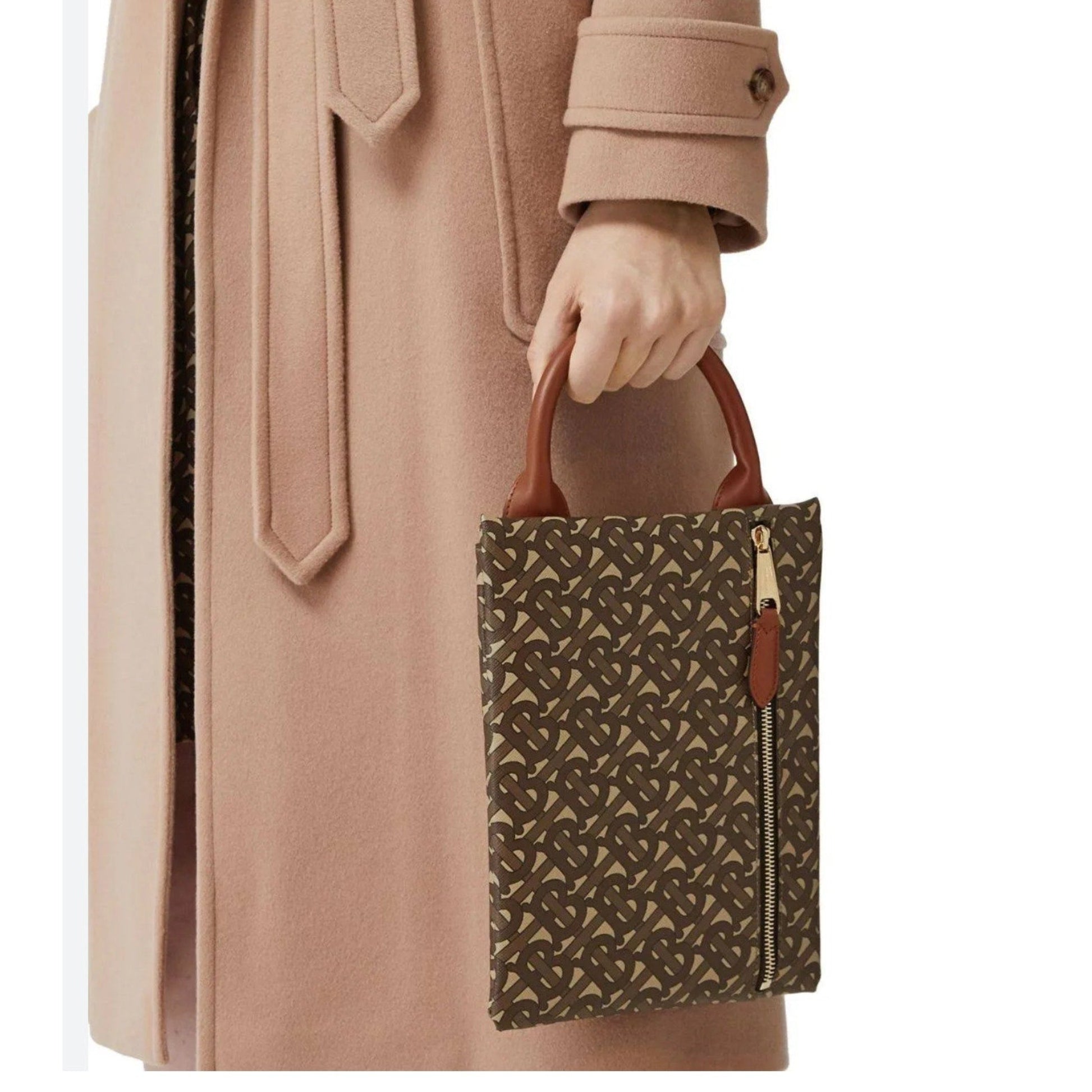 Person holding a patterned handbag with a beige coat
