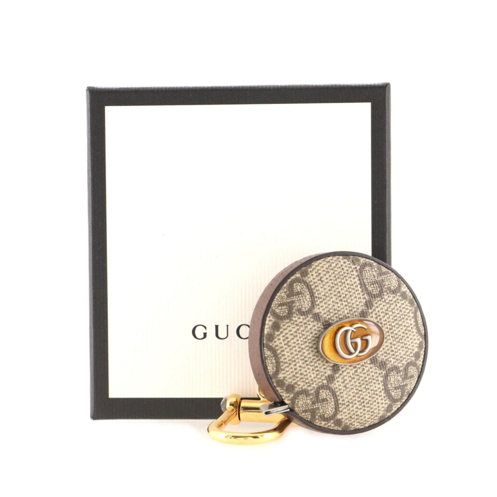 Round Gucci keychain with GG pattern and gold accents on a white background