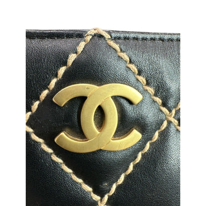 Close-up of a black leather product with gold stitching and Chanel logo.