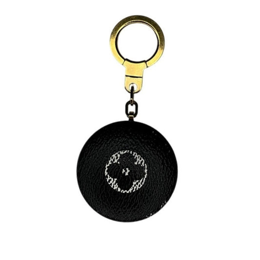 Black round keychain with gold ring on a white background