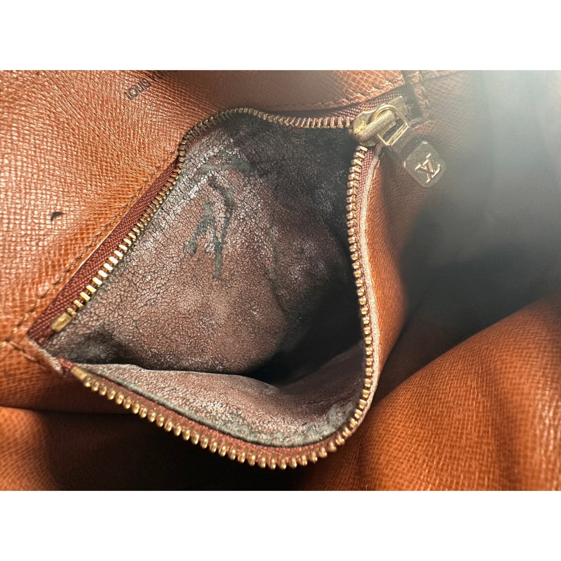 Close-up of a brown leather bag with a zipper, showing signs of wear.