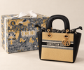 Beige and black GWP mini bag with gold-tone charms and presentation box